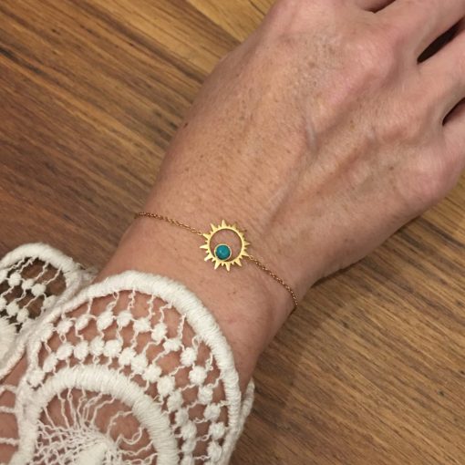 Bracelet souple Acier inoxydable couleur or avec un soleil central avec une petite perle couleur turquoise à l'intérieur.