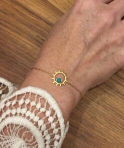 Bracelet souple Acier inoxydable couleur or avec un soleil central avec une petite perle couleur turquoise à l'intérieur.